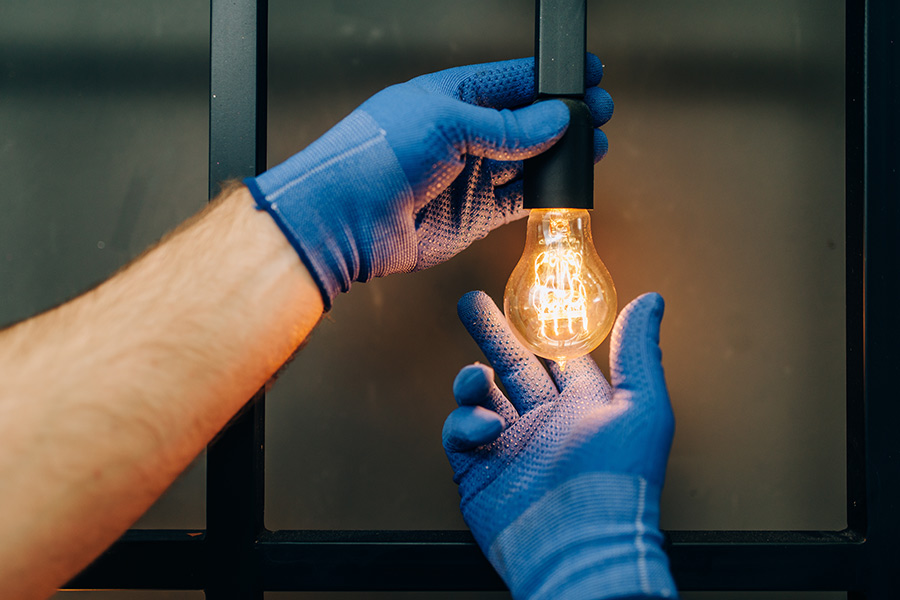 gloved-hands-screwing-in-light-bulb